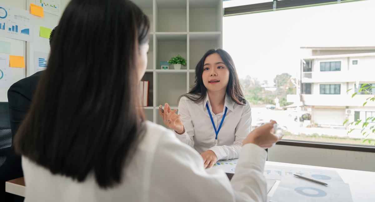 Ilustrasi dua orang fresh graduates sedang berdiskusi soal cara mengatasi kegugupan saat interview kerja. (Sumber: Envato)