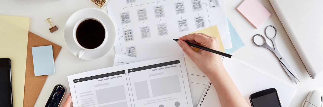 An employee making notes on project papers with a coffee cup, sticky notes, and sicsors