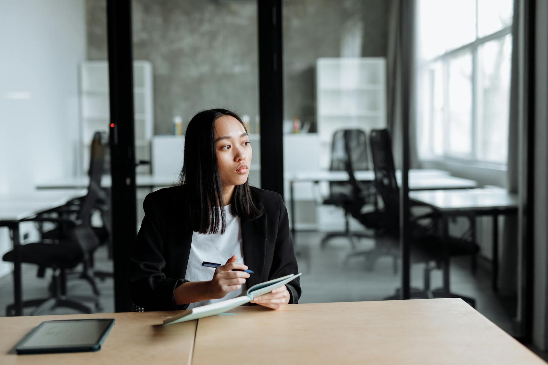 Young professional thinking while taking notes during a meeting in a modern office.