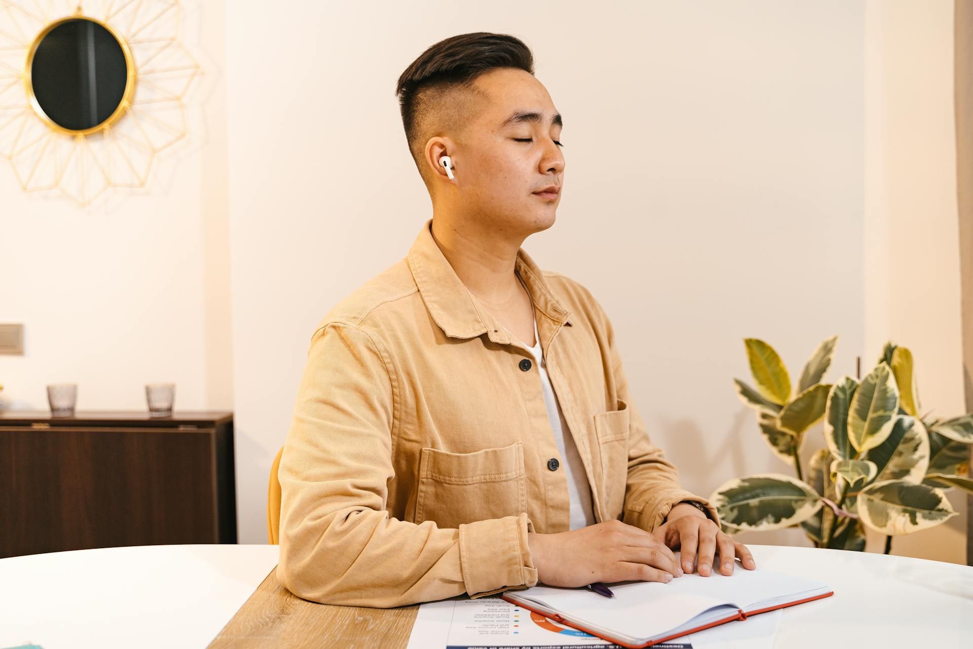 Young man meditating with eyes closed and earbuds in, practising mindfulness at work.