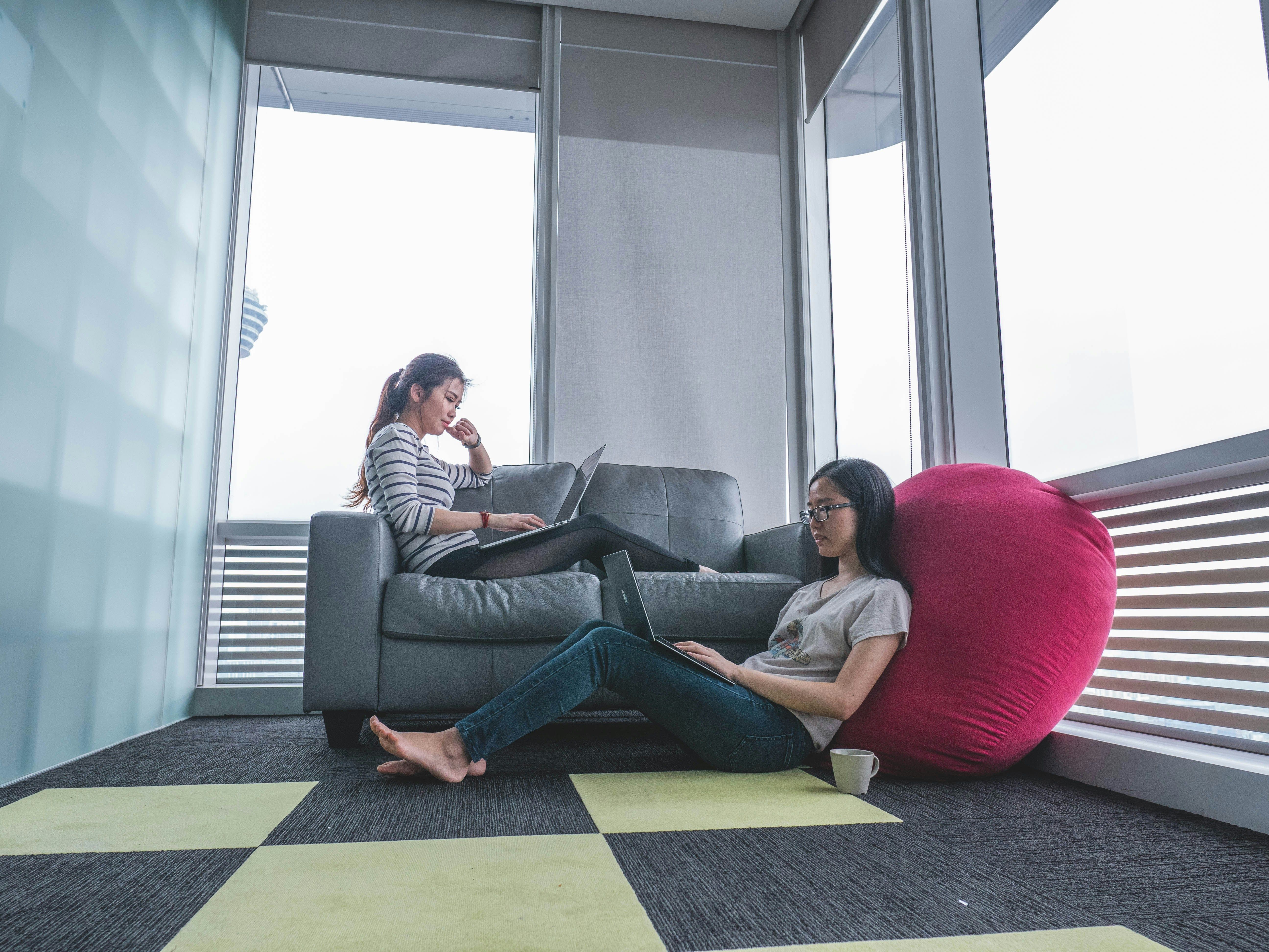  Two women working on laptops reading leadership quotes in a modern, relaxed office setting