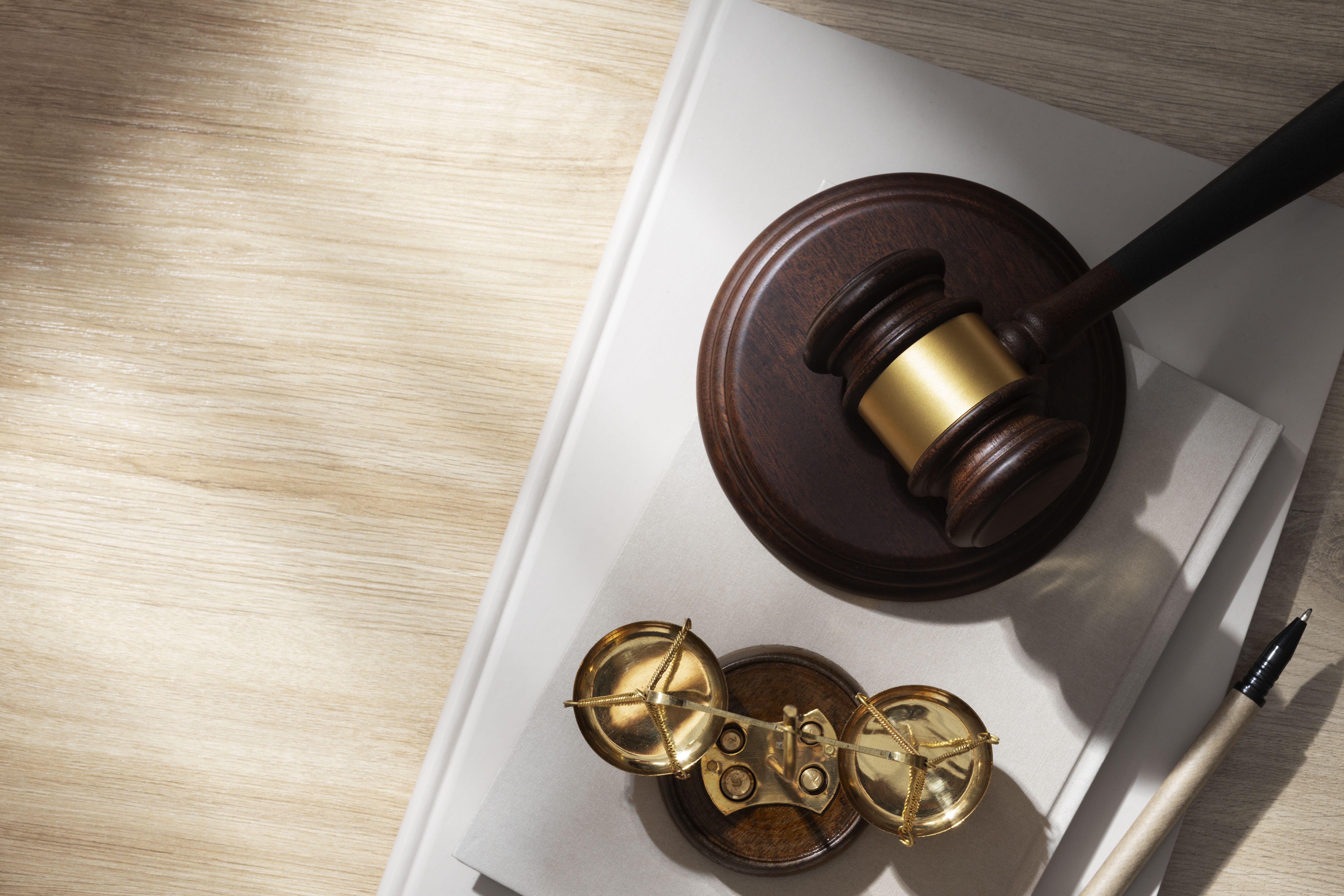Wooden judge's gavel, golden scales, and legal documents on a desk, symbolising law, justice, and legal compliance needed in employment letters. 