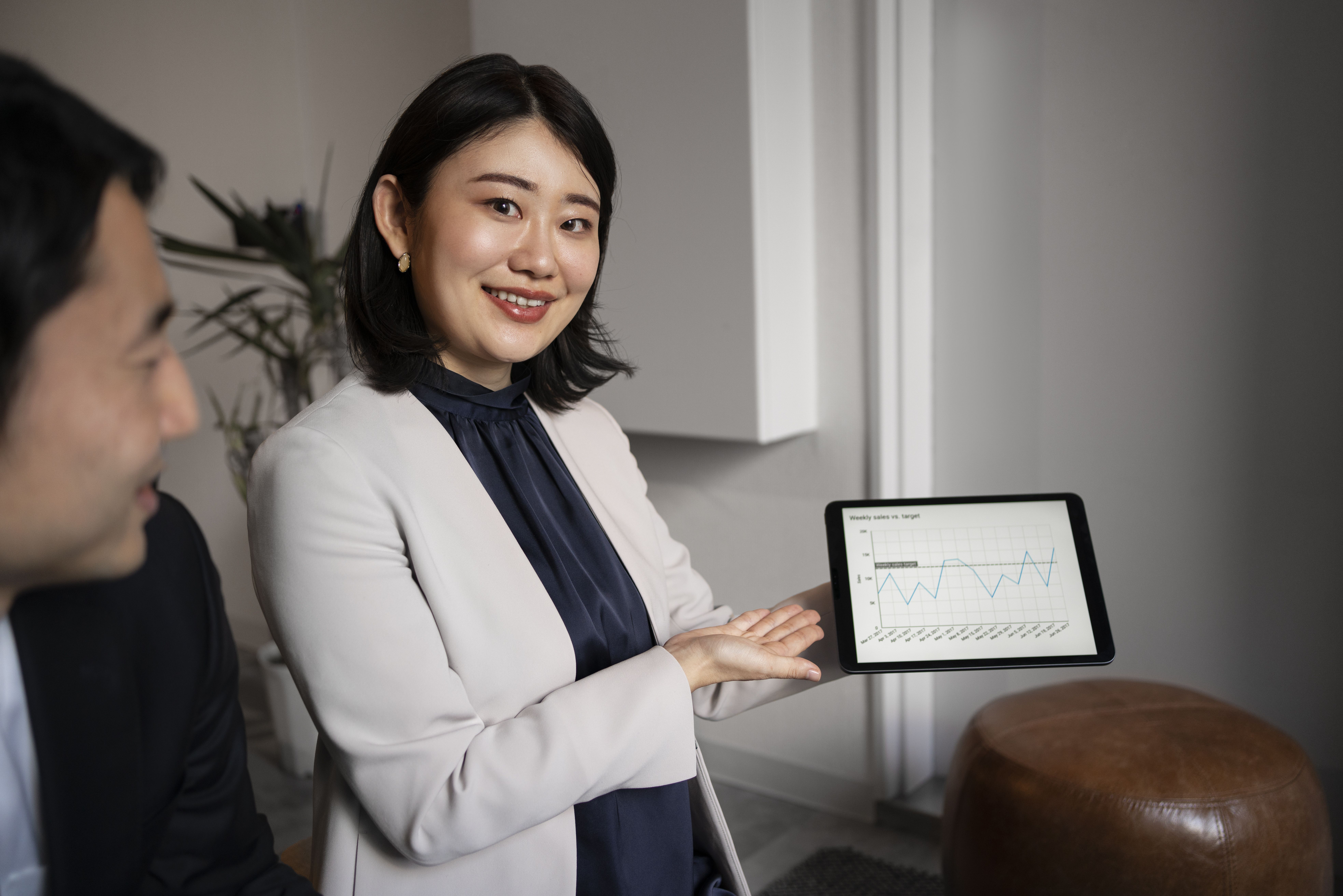 Wanita berpose dengan gawai tablet berisi grafik