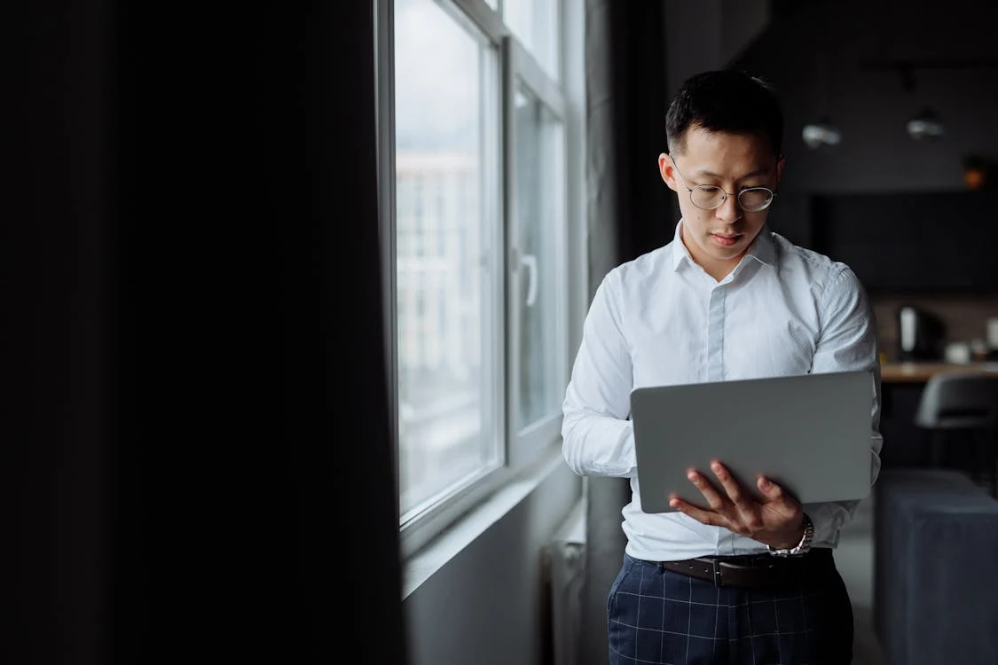 Seorang lelaki sedang menggunakan komputer riba di pejabat.