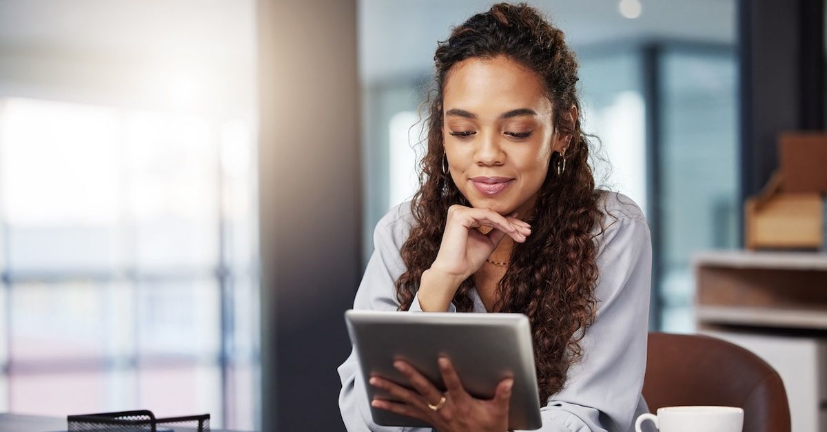 woman in a grey blouse holding a tablet