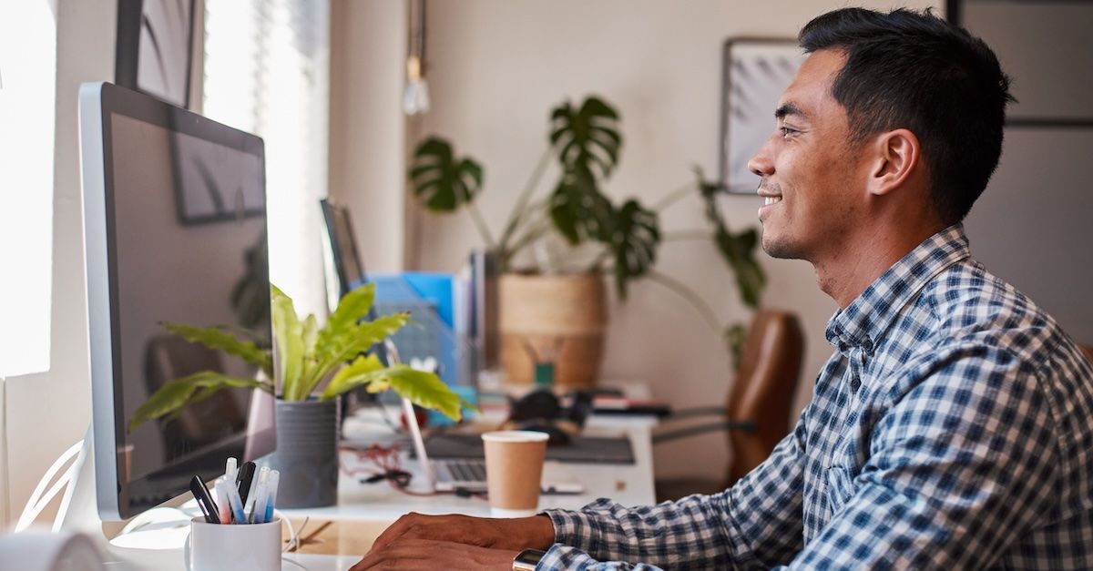 Man looking at computer plaid shirt working from home