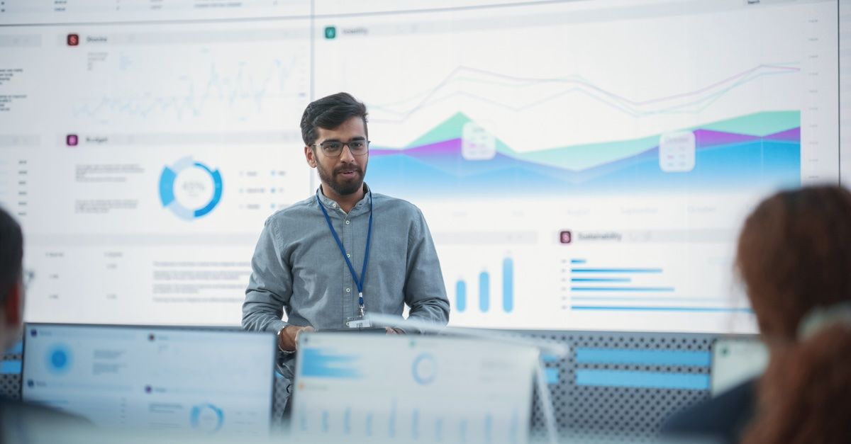 Man presenting a project recap with graphs in the background