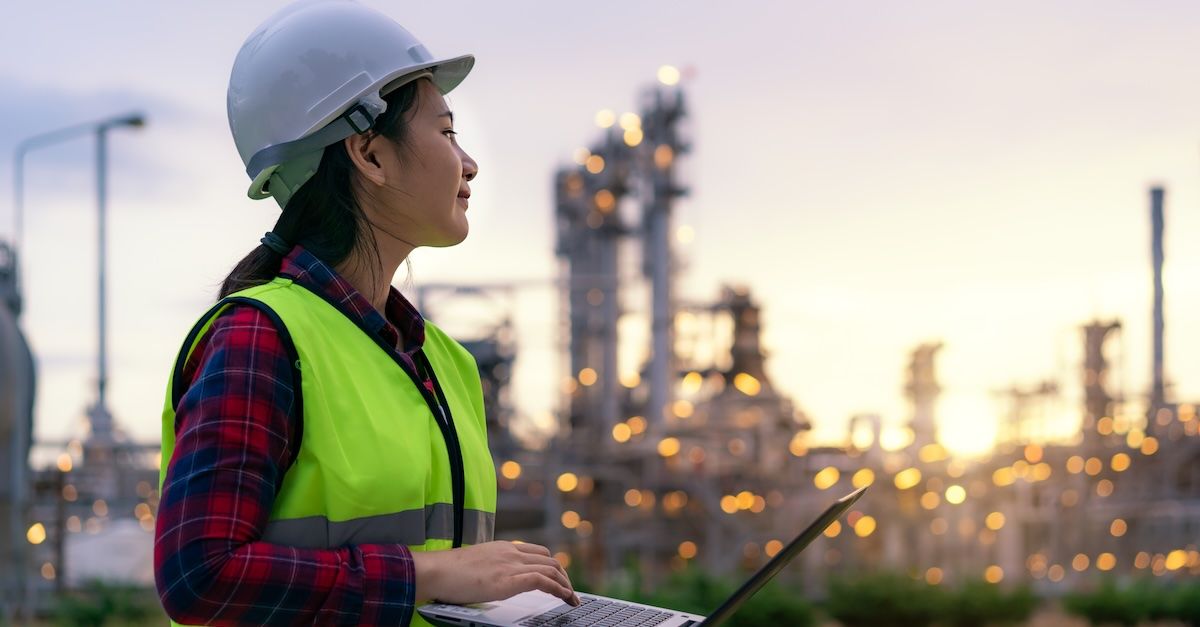 Woman in construction on a laptop wearing a hardhat