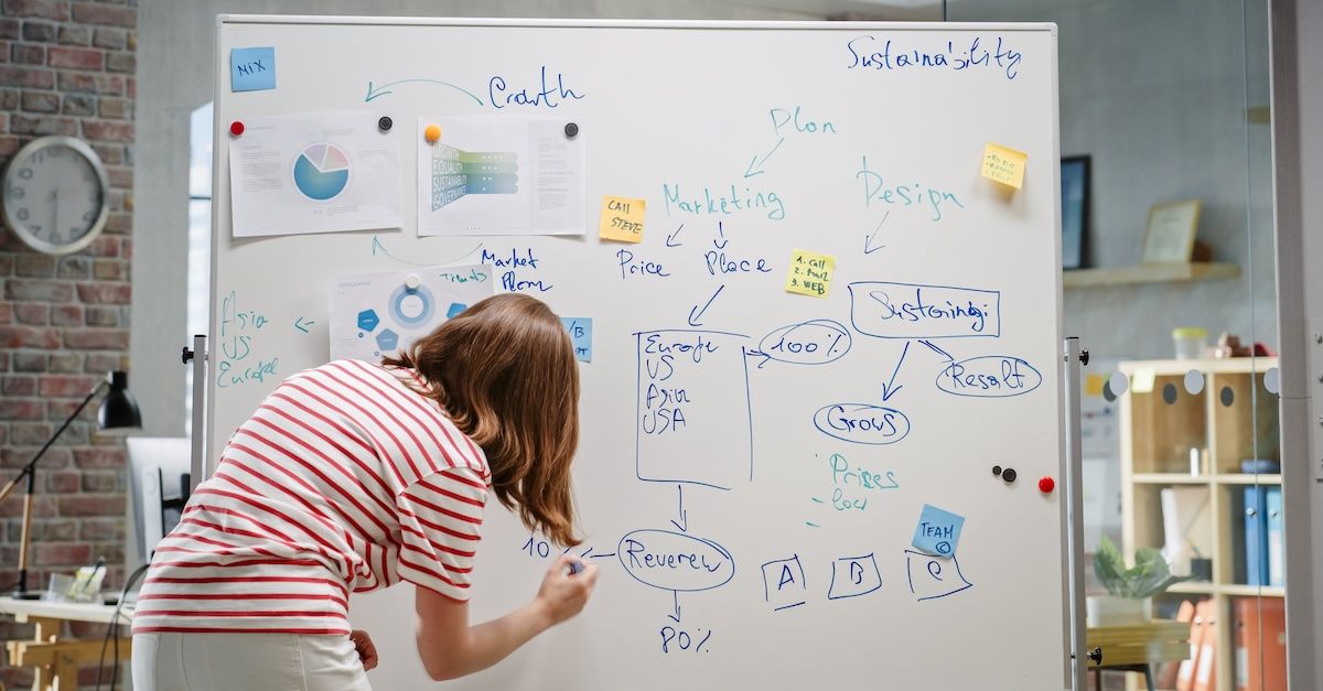 Woman writing on a white board at work