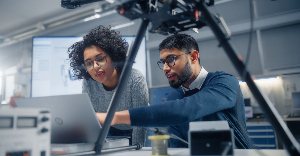 a man and woman with careers in IT work on video equipment and a computer