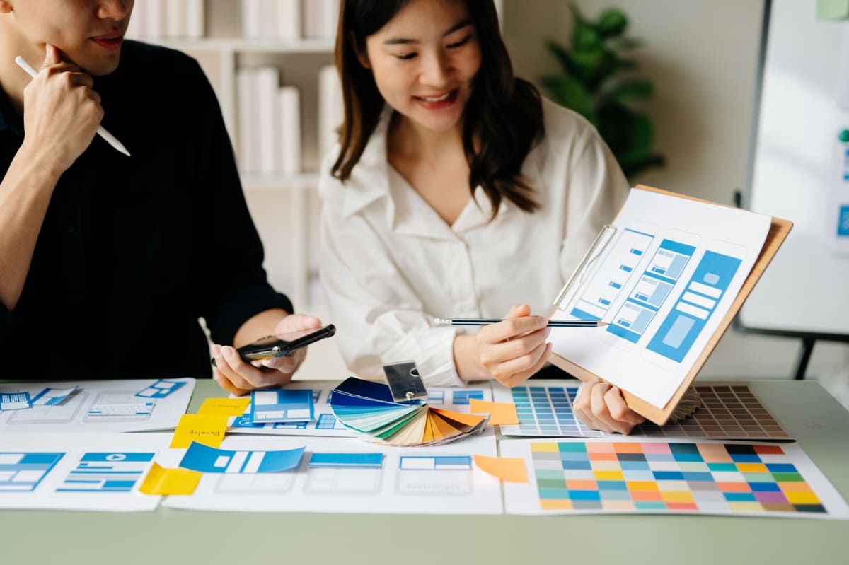 Seorang software developer sedang menjelaskan GUI atau Graphical User Interface kepada rekan kerjanya. (Sumber: Envato)
