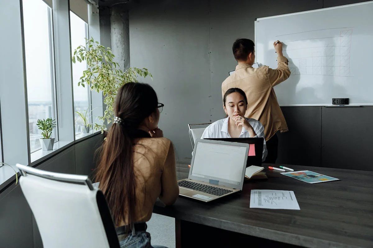 Tiga orang karyawan startup sedang mengikuti meeting.