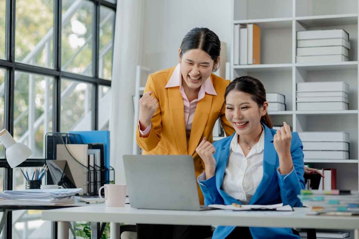 Ilustrasi dua orang karyawan tampak bahagia setelah merekomendasikan teman mereka melalui employee referral program. (Sumber: Envato)