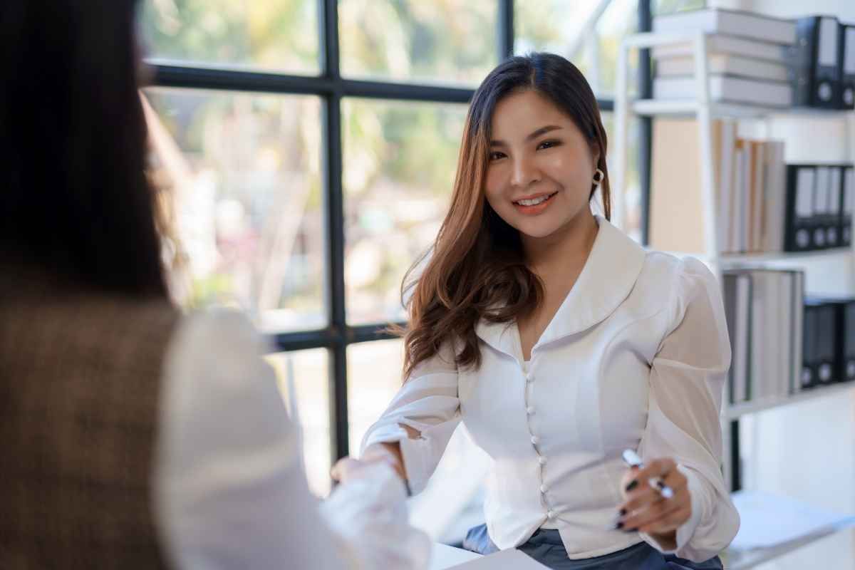 Seorang pelamar kerja wanita berjabat tangan dengan HRD perusahaan pada sesi panel interview. (Sumber: Envato)