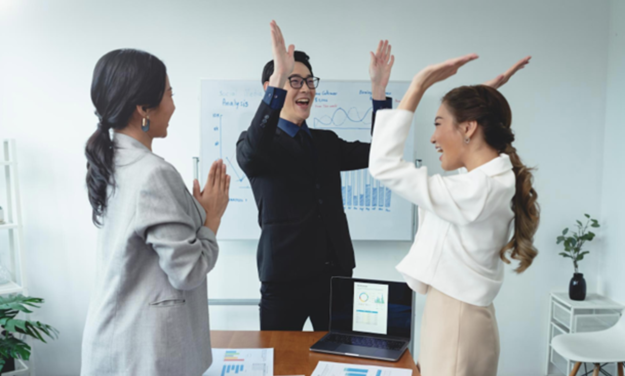 A group of business colleagues enthusiastically celebrates a well-deserved promotion in the office