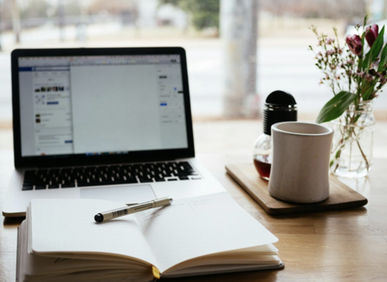 Image of pen and paper in front of a laptop