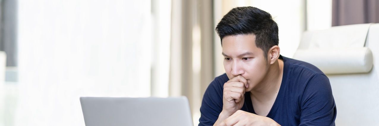 A man intently focusing on content displayed on a laptop screen