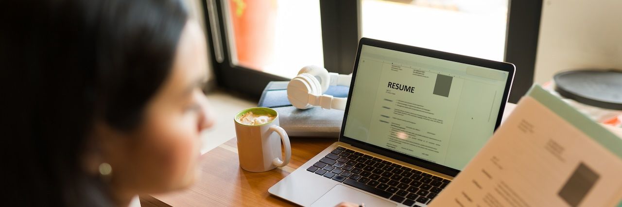 resume on a laptop and a woman holding a copy