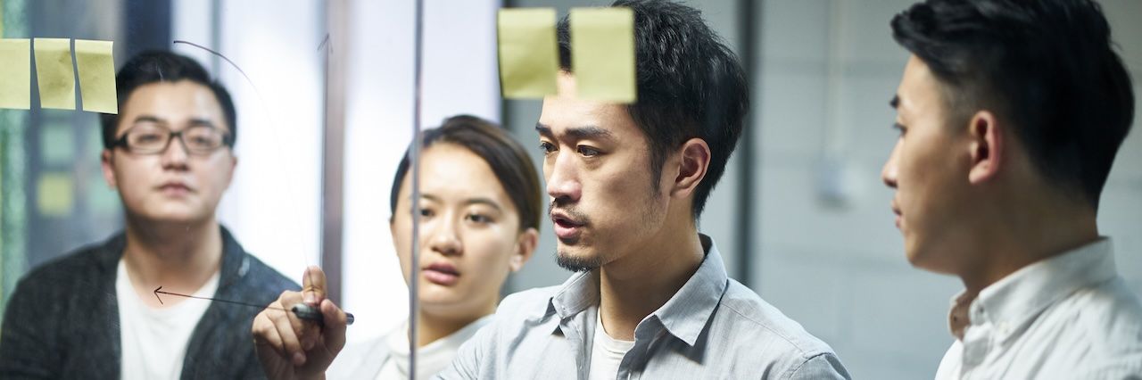 Coworkers writing on an idea board