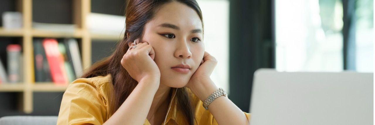 Woman in the office in a yellow shirt looking at her computer