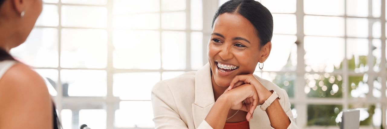 Woman working with a tan blazer and smiling