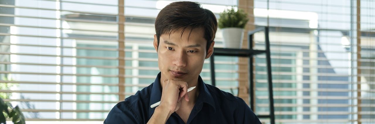 man thinking with the blinds open behind him