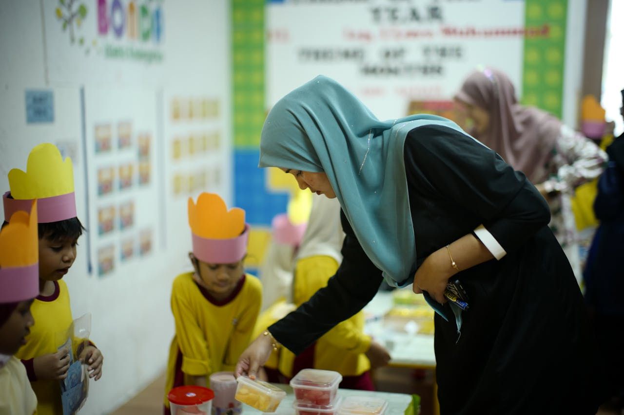 Pegawai perkhidmatan pendidikan sedang membimbing murid dalam sesi pembelajaran di institusi kerajaan.