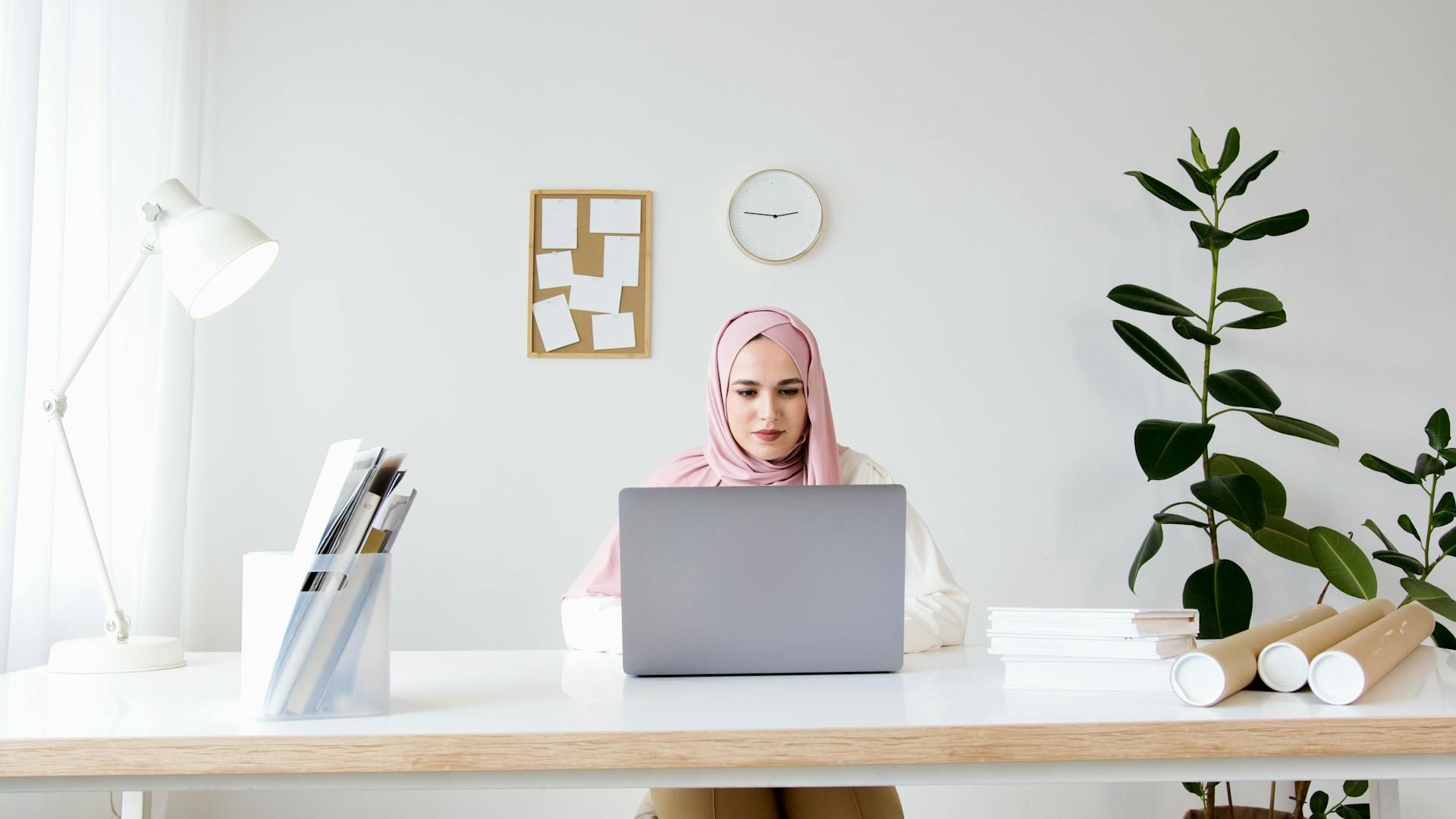 Wanita profesional memberi pembentangan di hadapan papan putih dalam suasana korporat.