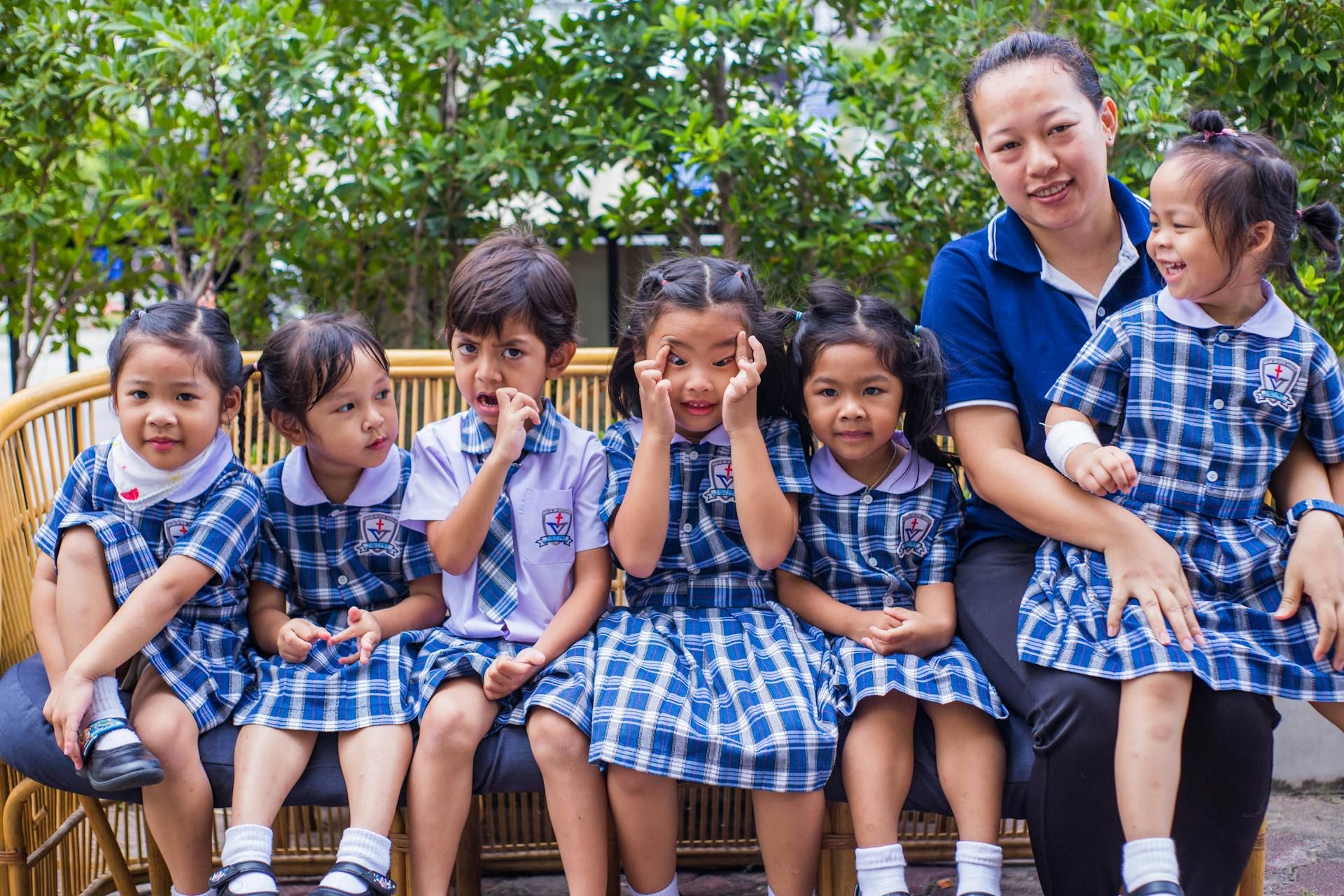 Kanak-kanak tadika beruniform sekolah dengan seorang guru.