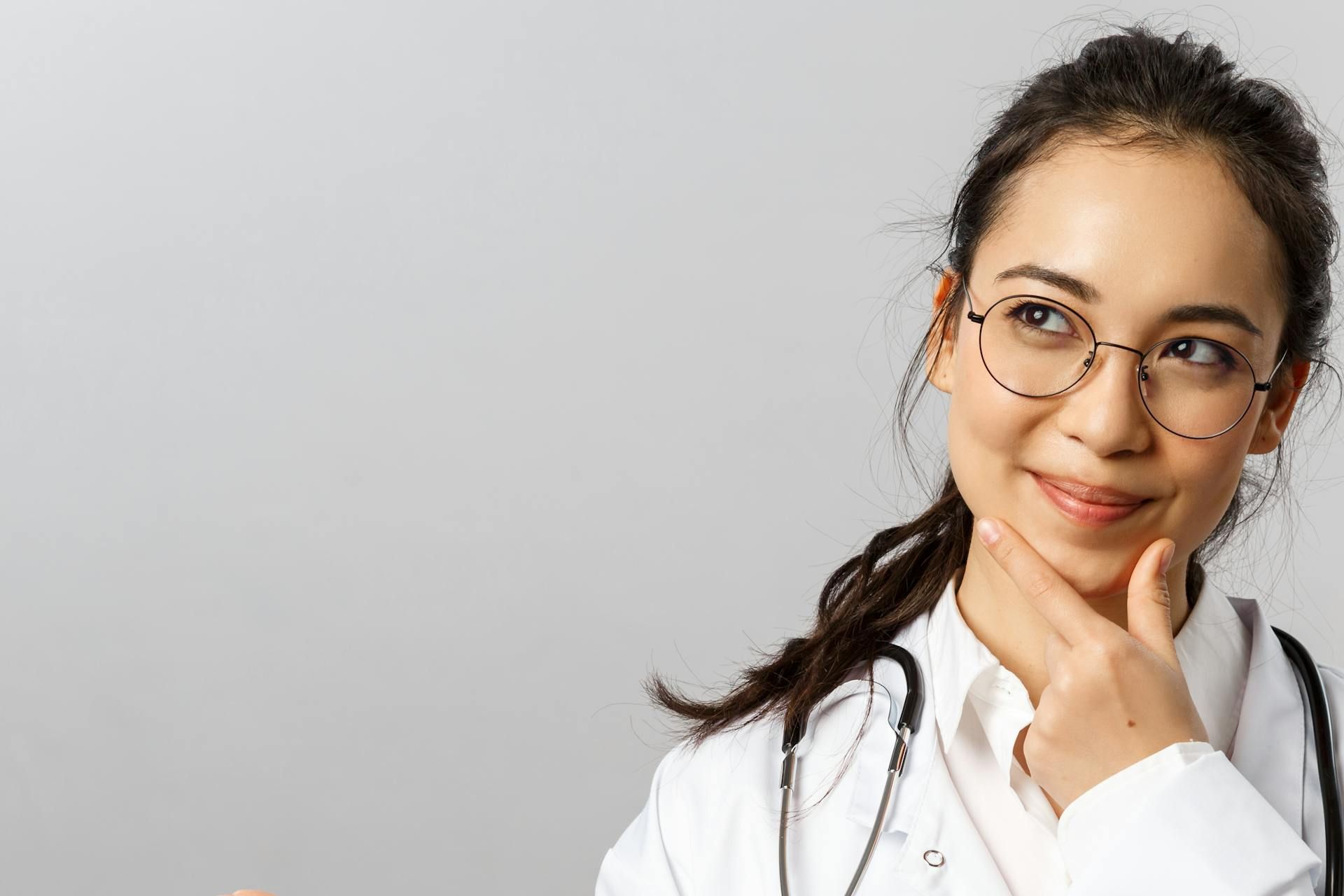 Wanita profesional dalam pakaian doktor sedang berfikir dengan ekspresi yakin.