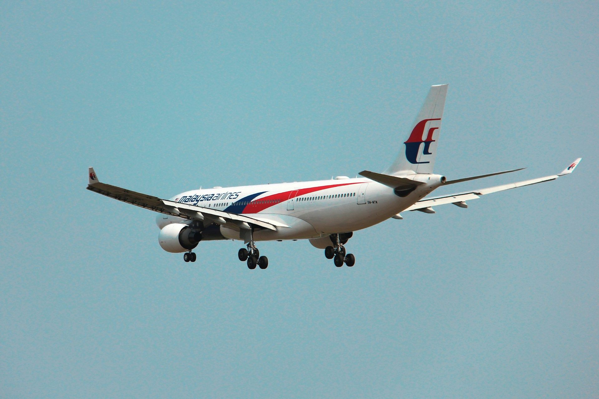 Pesawat Malaysia Airlines sedang bersedia untuk mendarat, simbol perjalanan kerja ke luar negara.