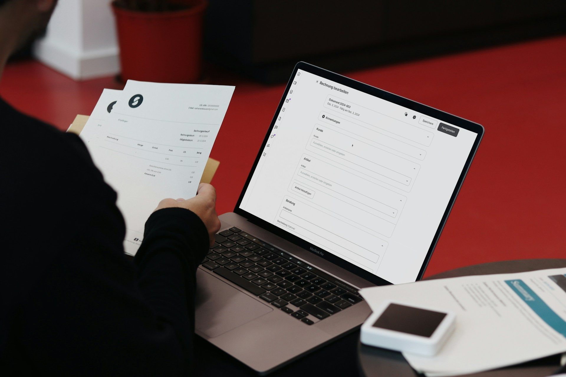 Seorang pekerja sedang menguruskan dokumen penting dengan komputer riba dan kertas kerja untuk kerja sambilannya yang dilakukan atas talian.