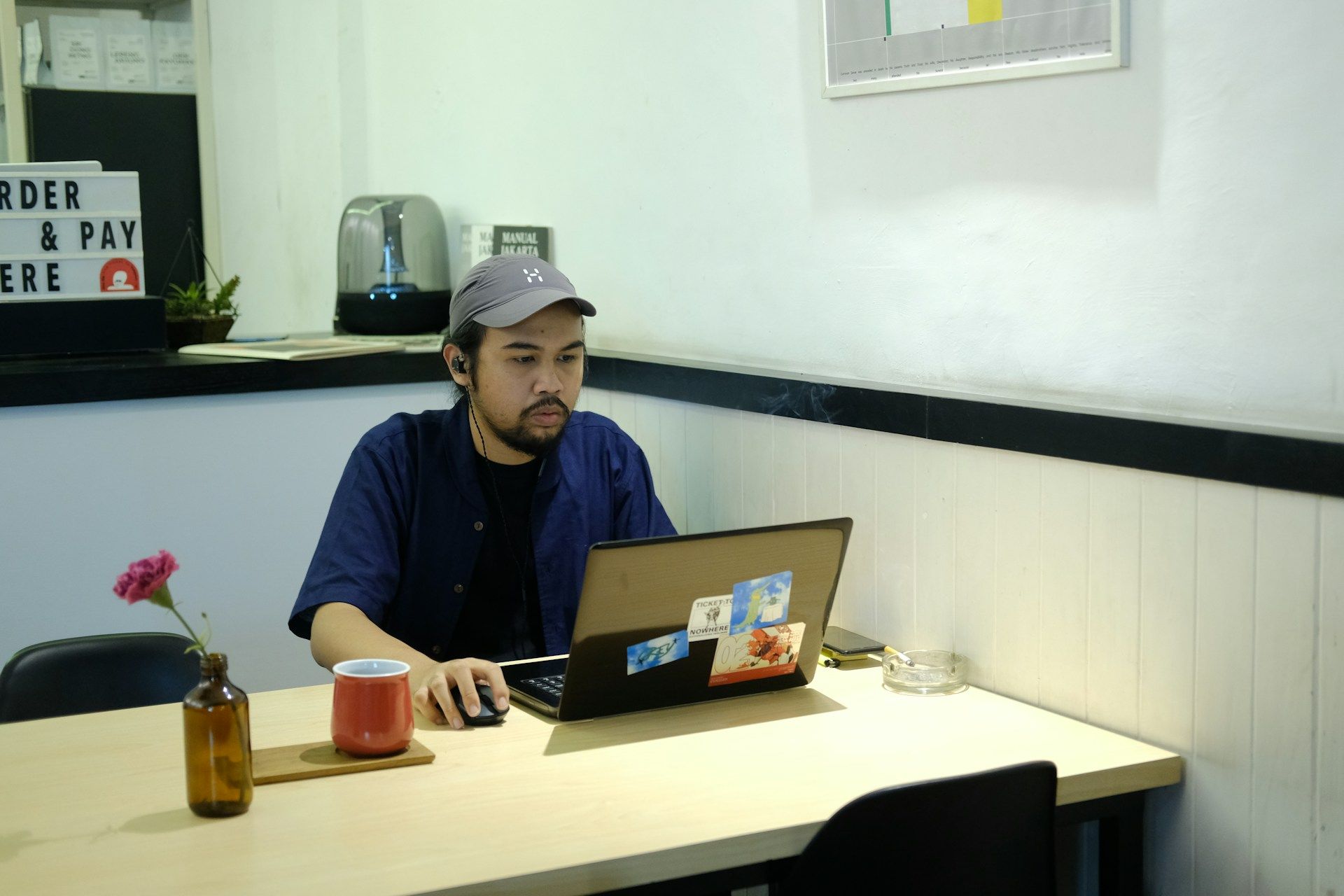 Seorang lelaki bekerja tugasannya di kafe menggunakan komputer riba.
