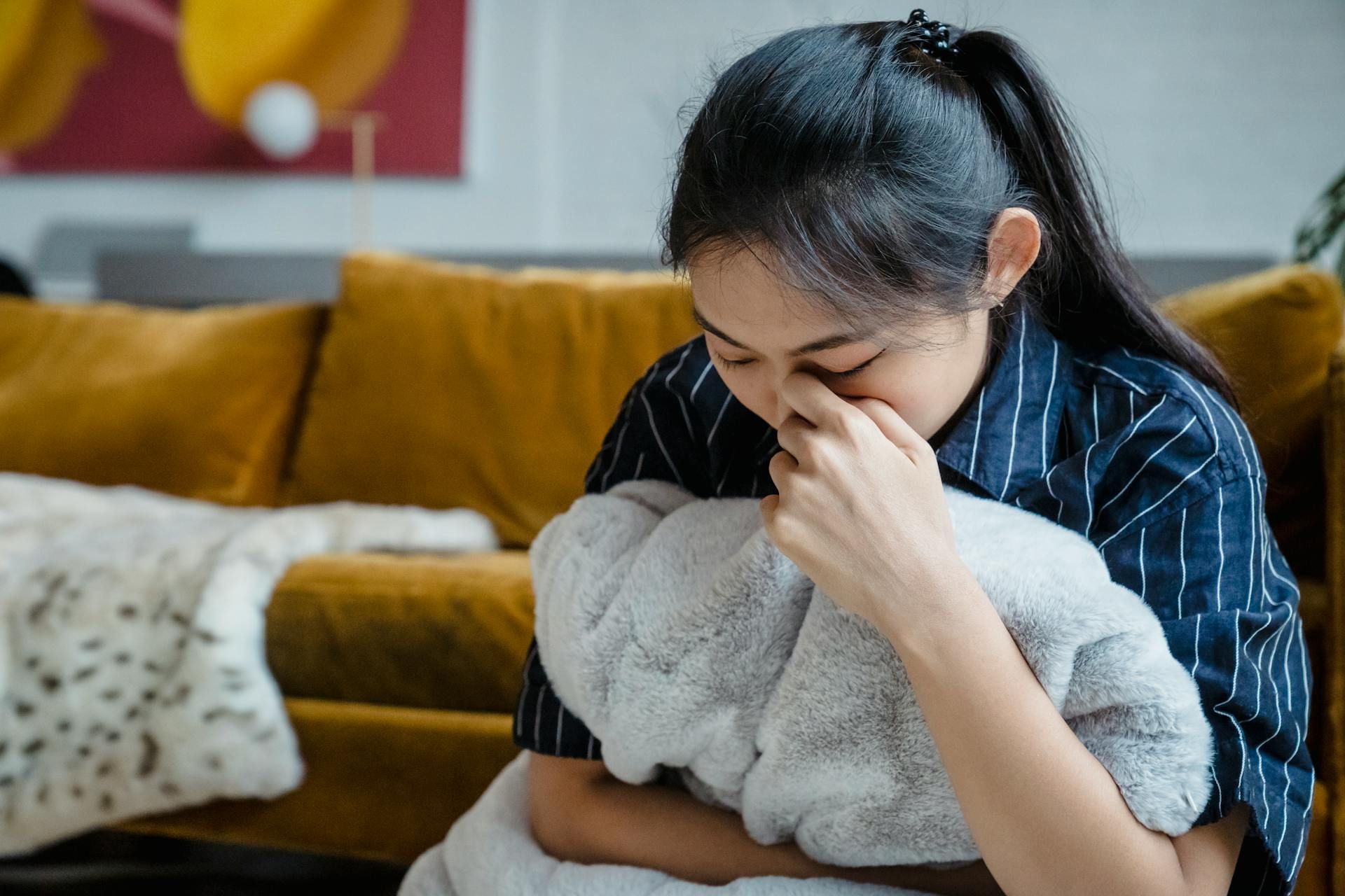 Seorang wanita sedih memeluk selimut.