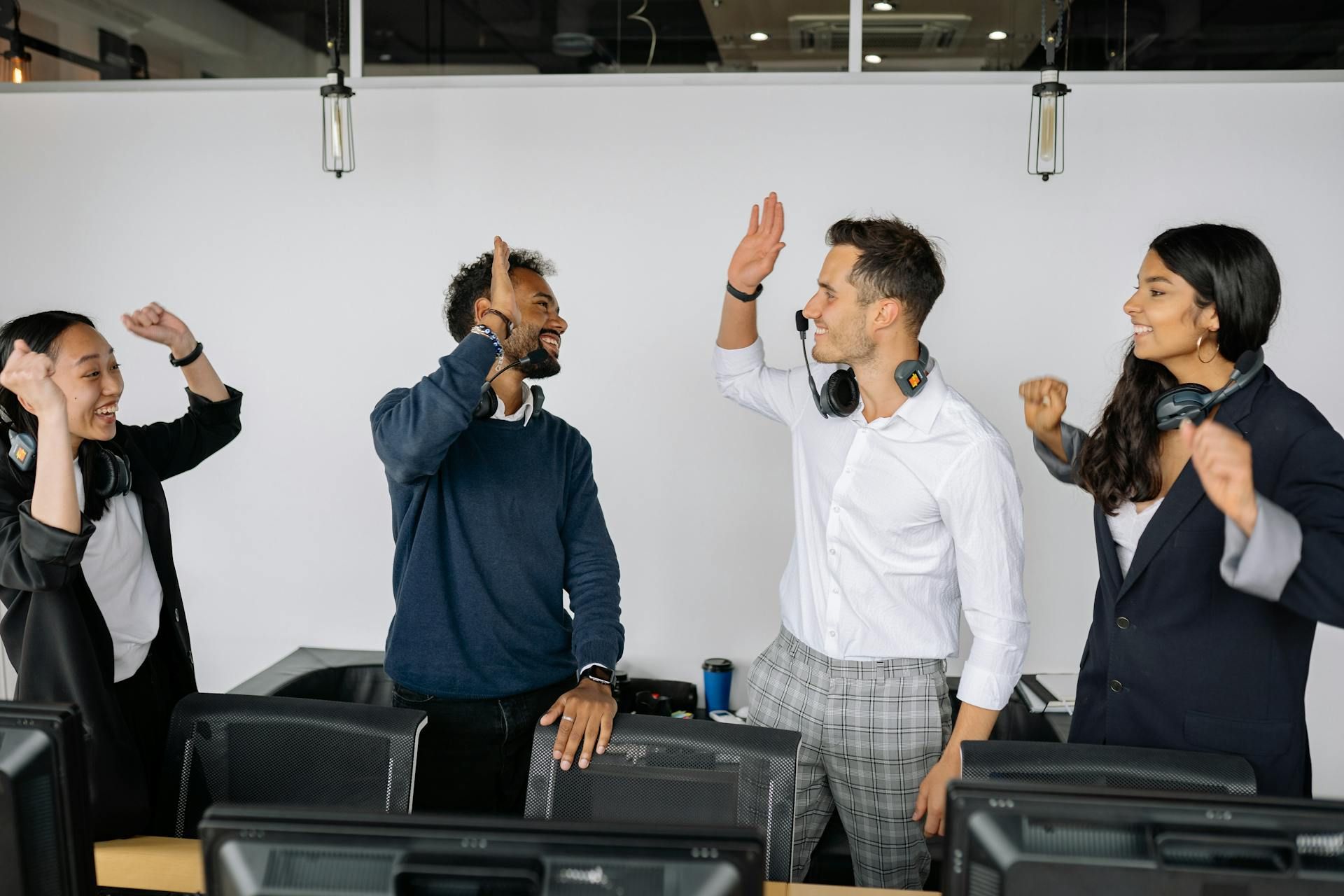 A group of colleagues giving high-fives in the office, celebrating a team achievement.