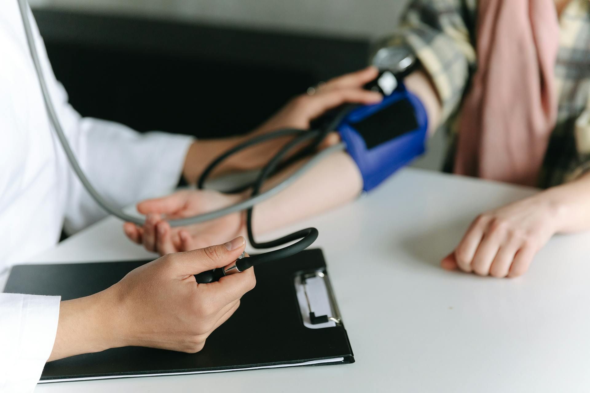 Seorang doktor sedang mengukur tekanan darah pesakit menggunakan sphygmomanometer.