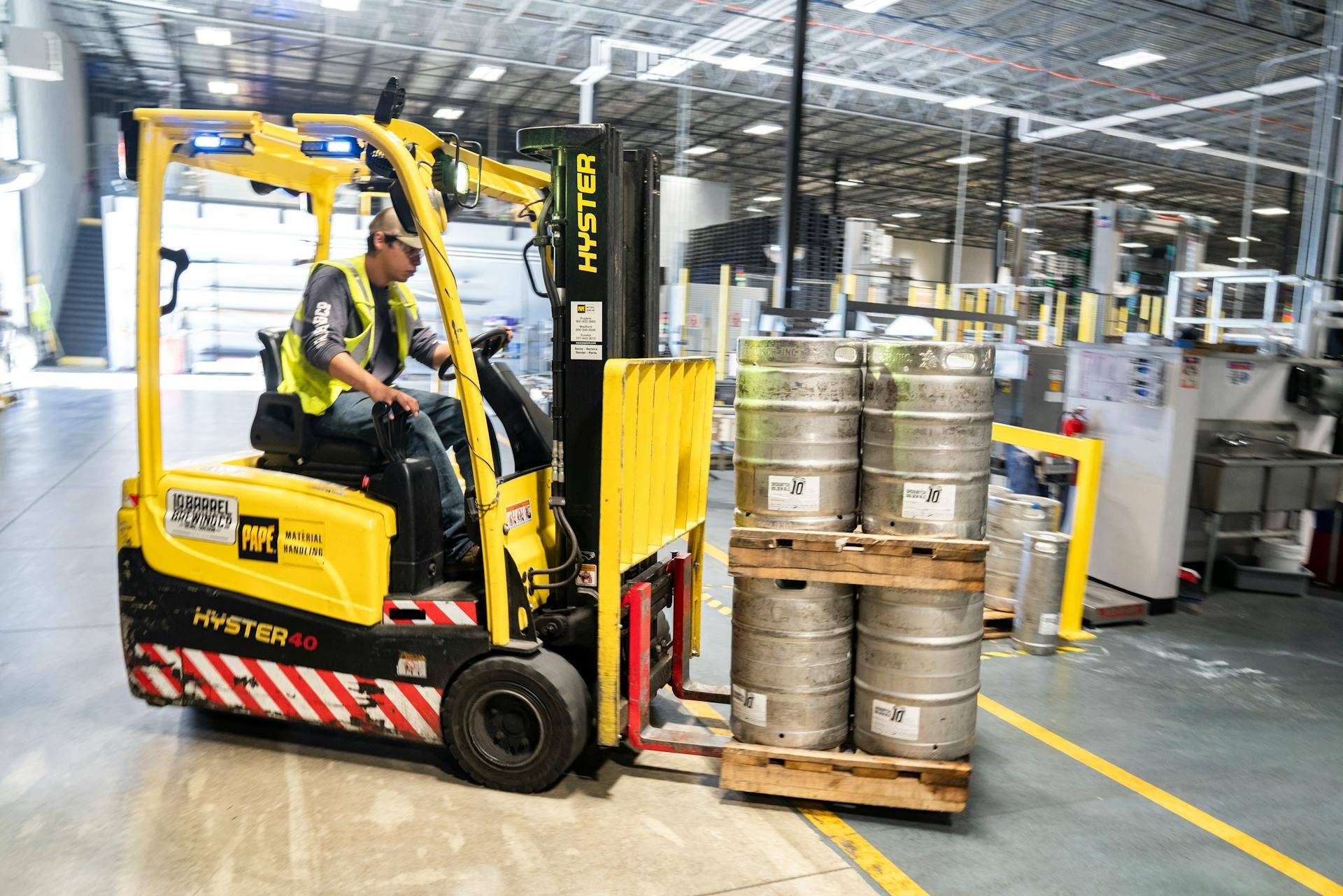 Pekerja logistik mengendalikan forklift untuk mengangkat barangan di gudang.