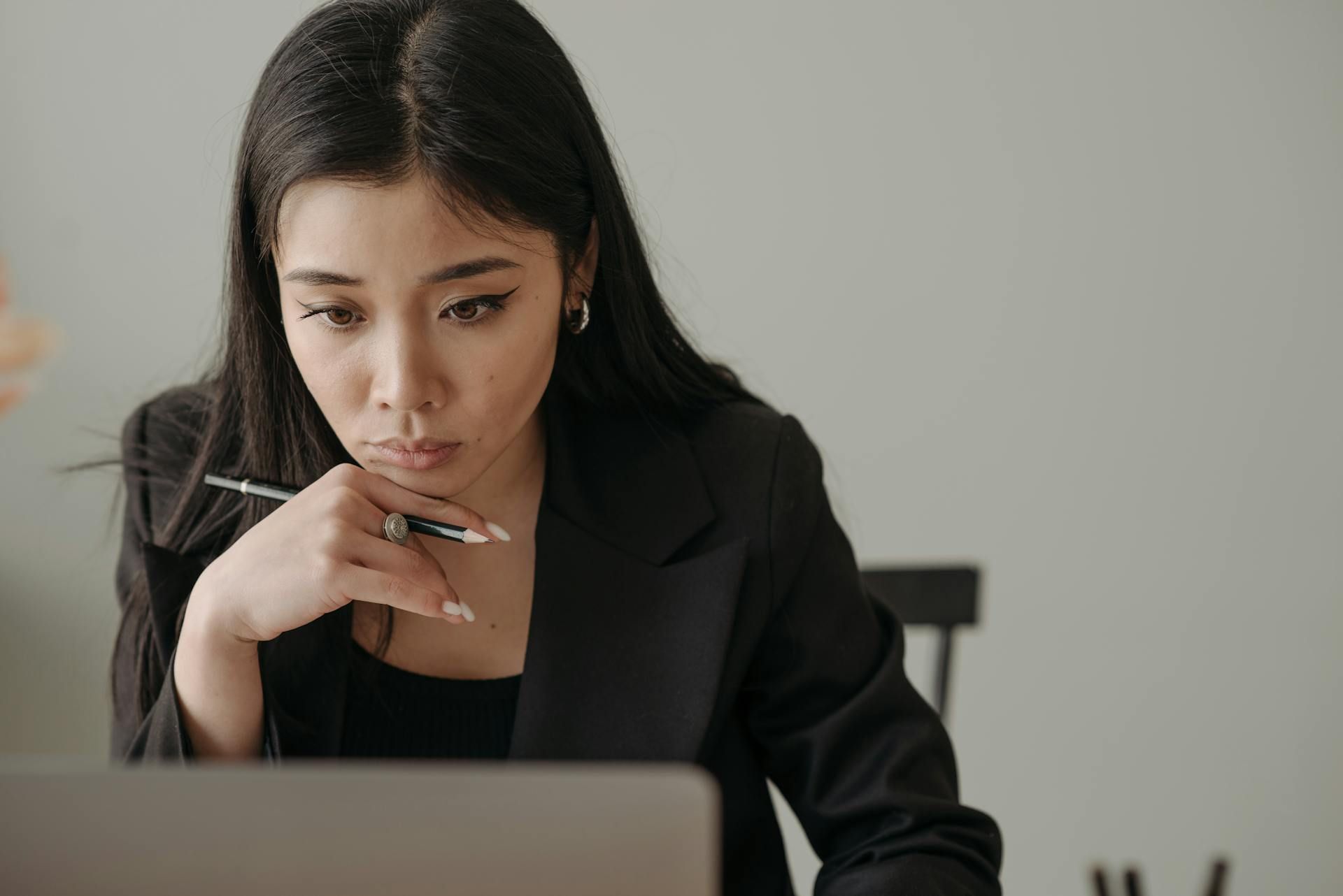 Wanita dalam sut hitam melihat komputer ribanya
