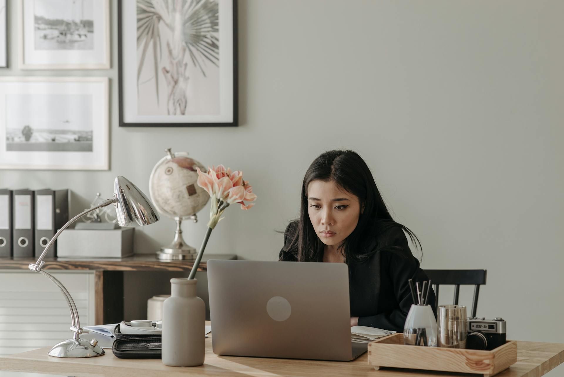 Seorang wanita berbaju hitam sedang menggunakan laptop.