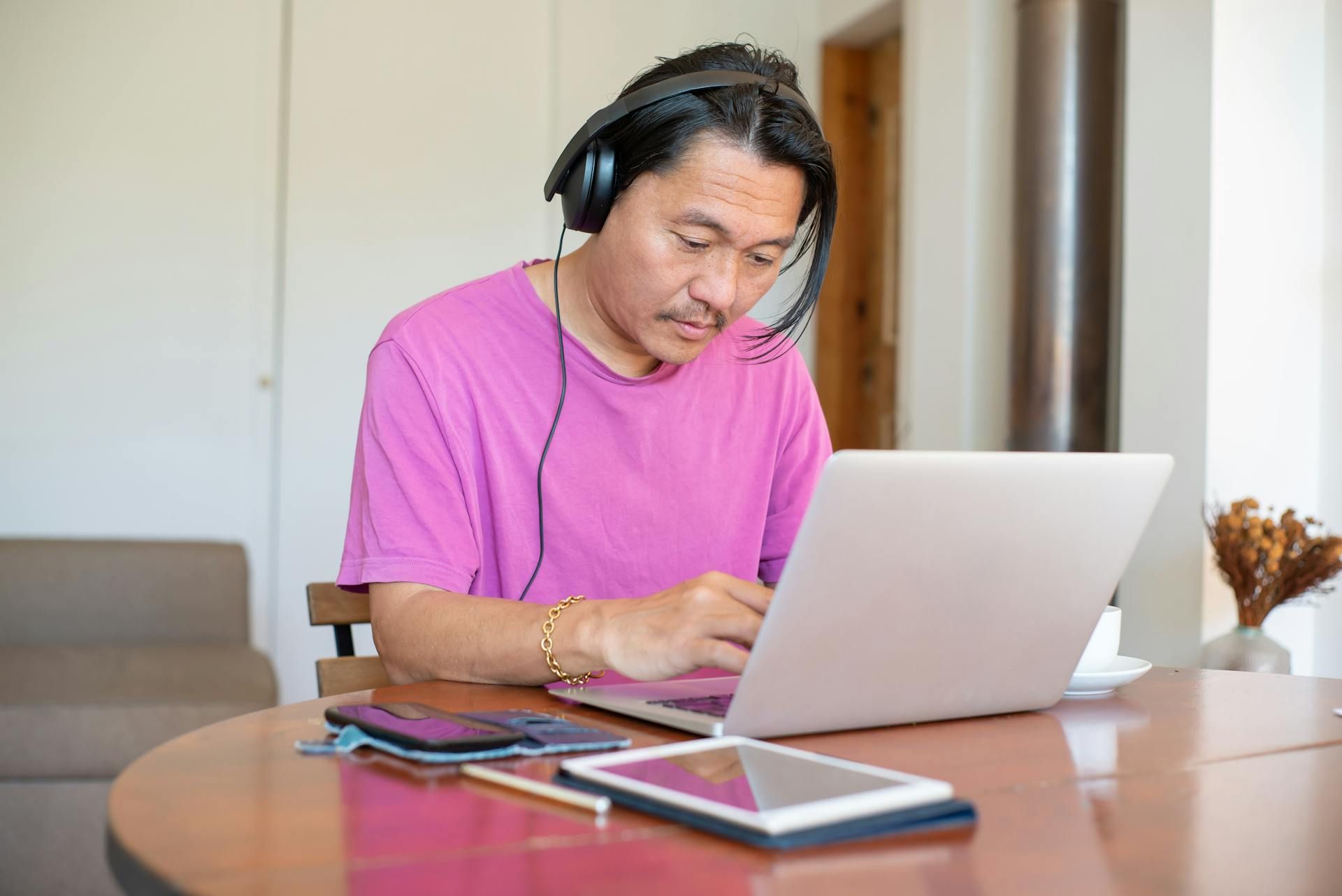 Seorang lelaki memakai headset sedang menaip pada komputer riba di meja kerja.