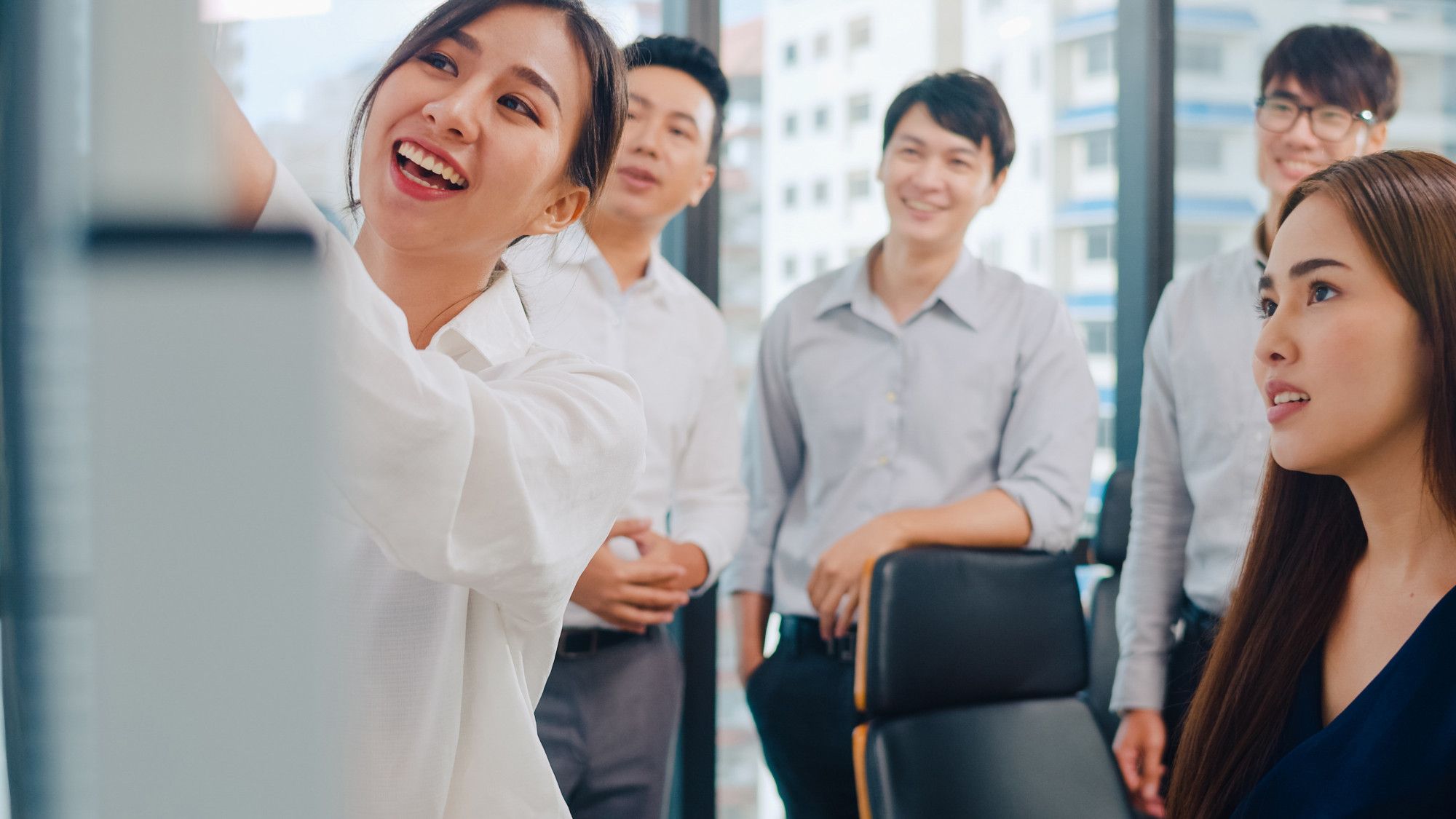 Professionals reviewing a whiteboard filled with catchy tagline examples, one person pointing out a great example that stands out in a branding strategy session.
