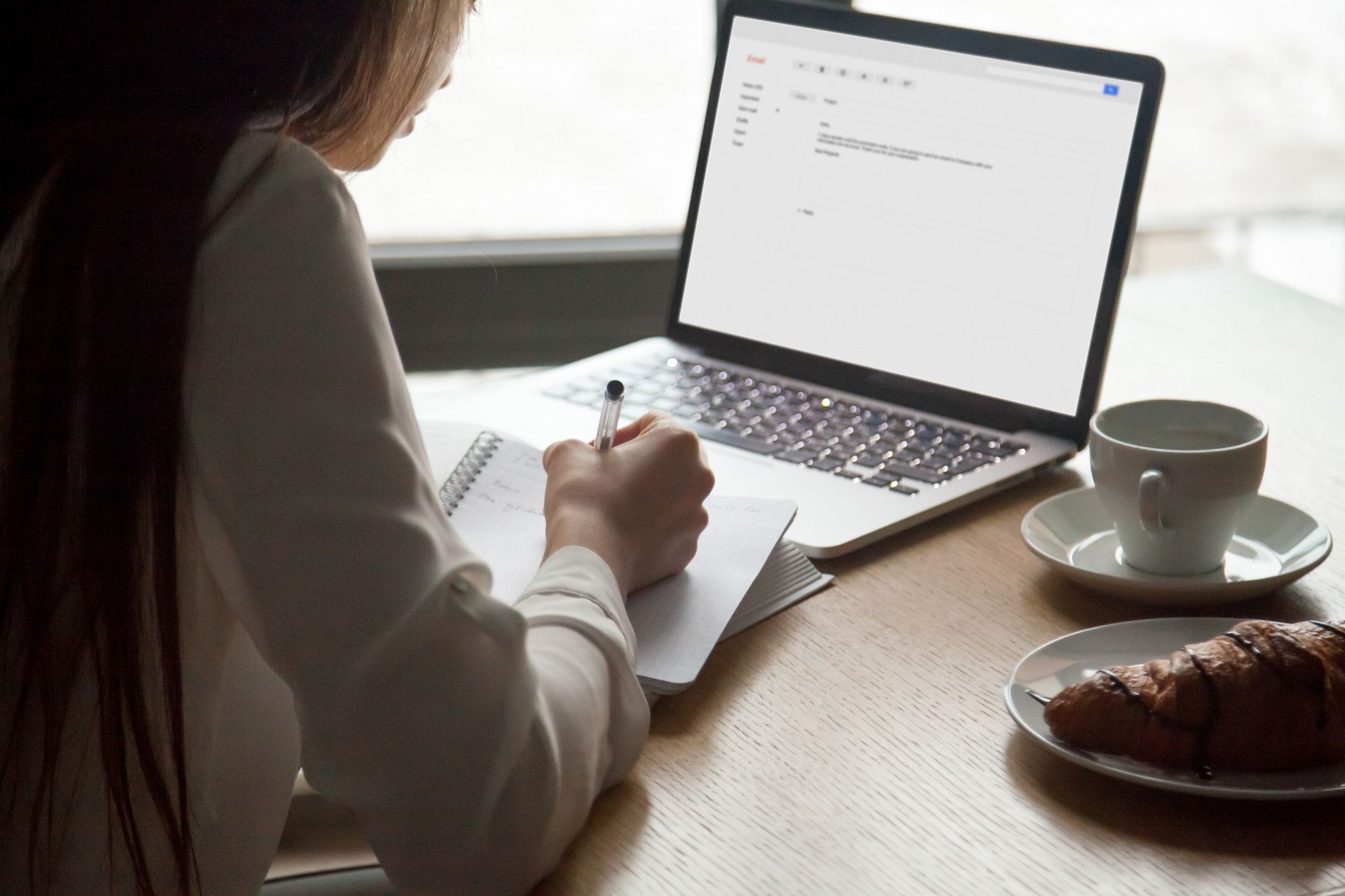 A woman at a training event, preparing to craft a memo with a professional tone, and writing sample memos on her notebook.