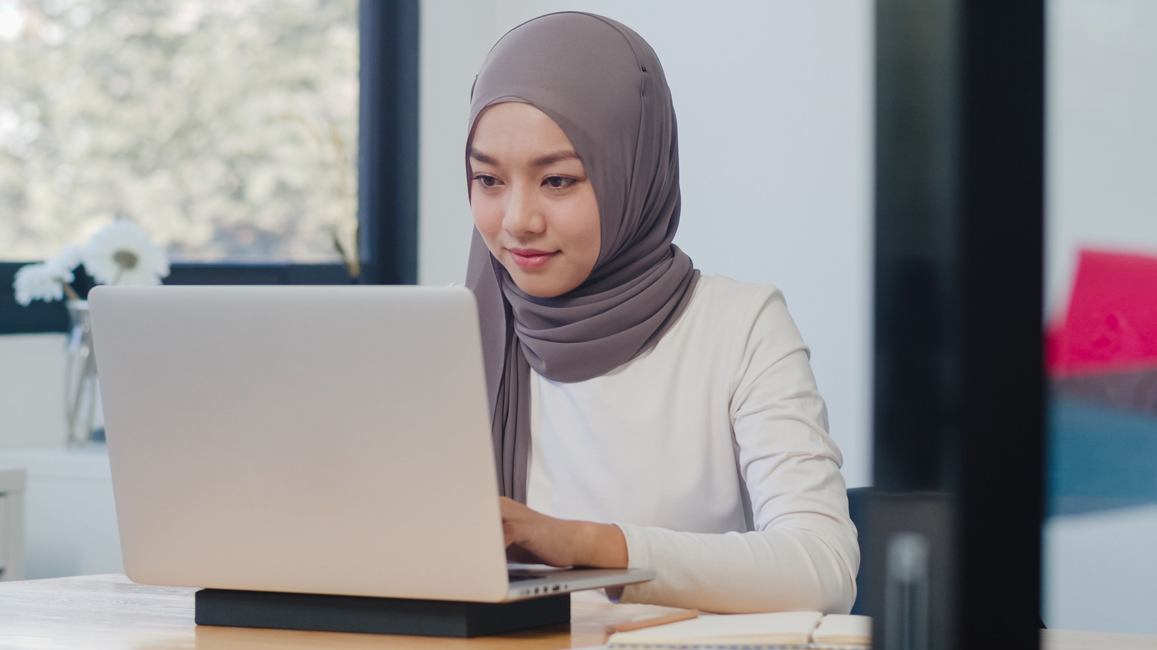 Seorang perempuan sedang menggunakan laptop untuk mencari resume lepasan STPM.