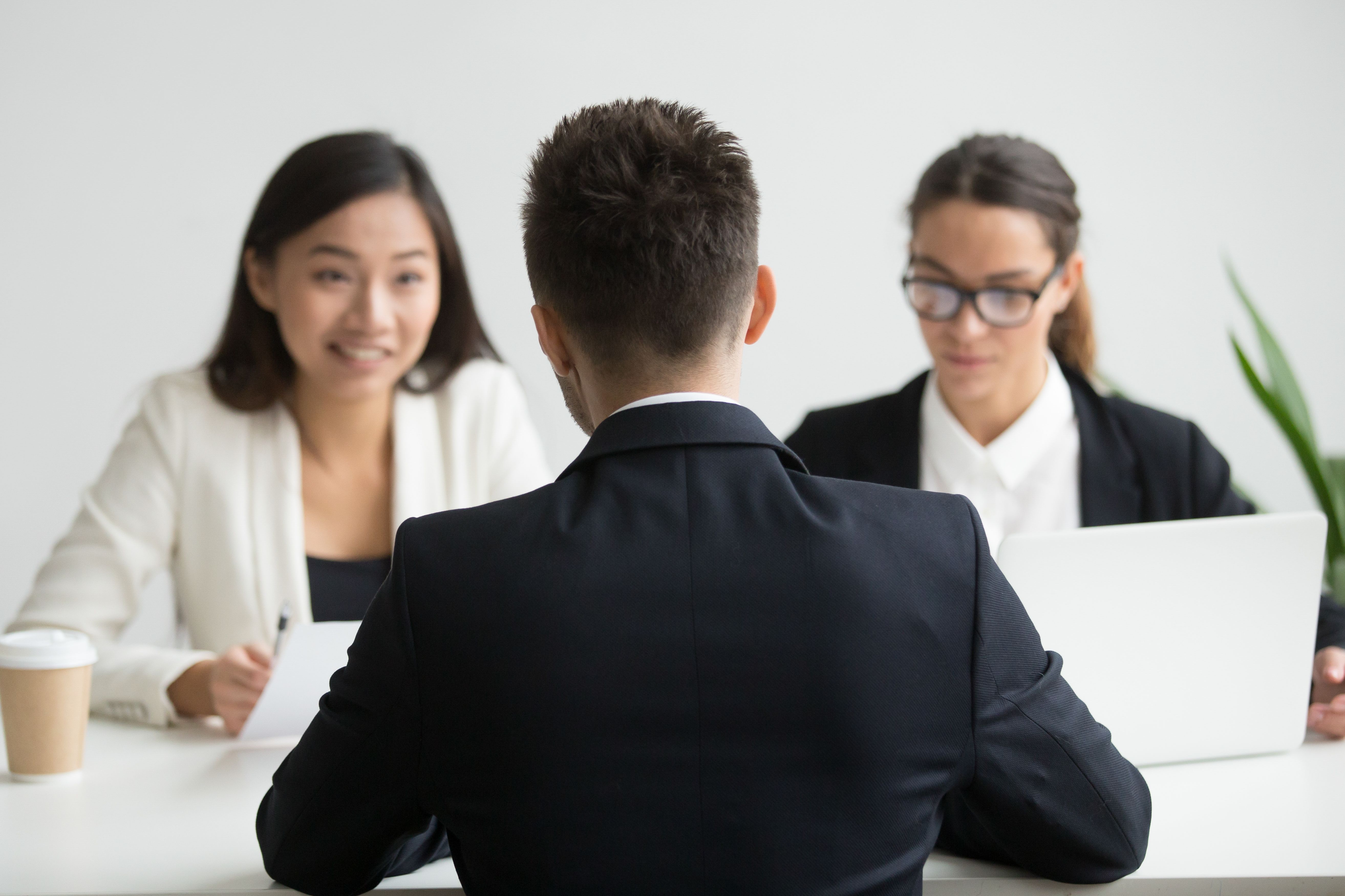 A male job candidate being interviewed by two female hiring managers, before sending a follow up email after interview.
