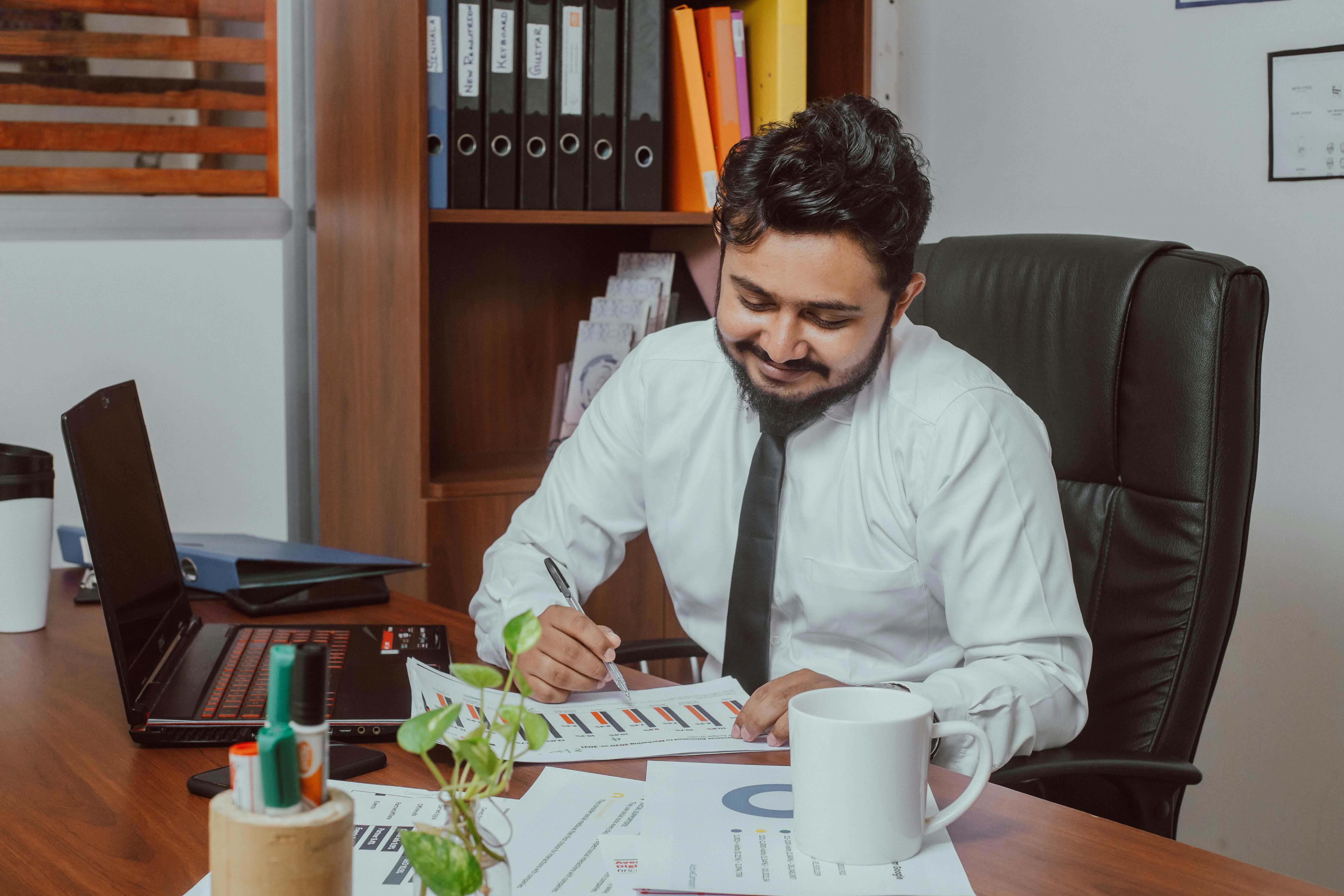 Professional reviewing charts at a desk, reflecting management, understanding trends, and continuous improvement.