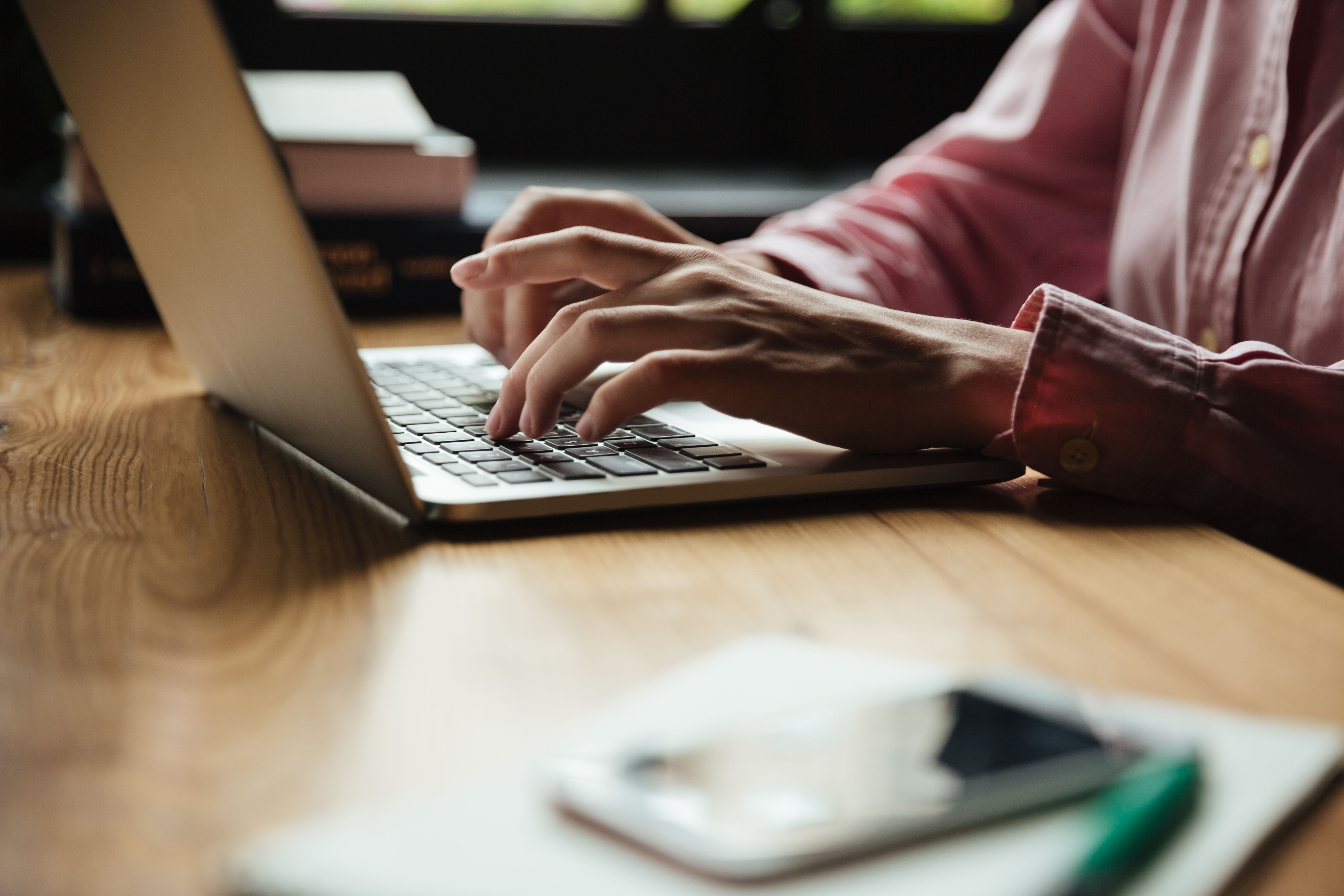Close-up of a person typing on a laptop, drafting a professional resignation letter example with a 2-week notice period.