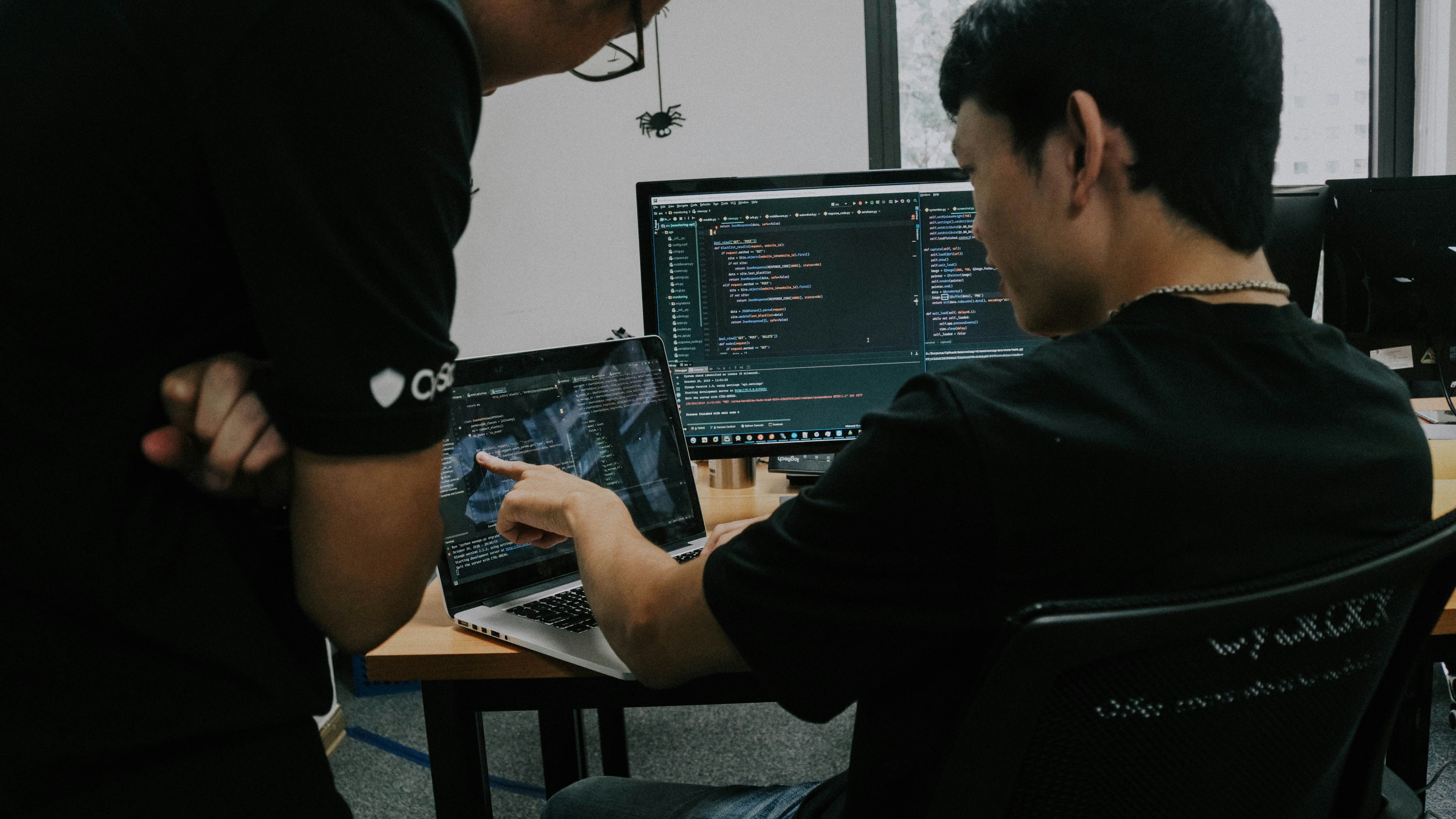 Dua jurutera membincangkan tentang data analisa menggunakan laptop dan komputer.