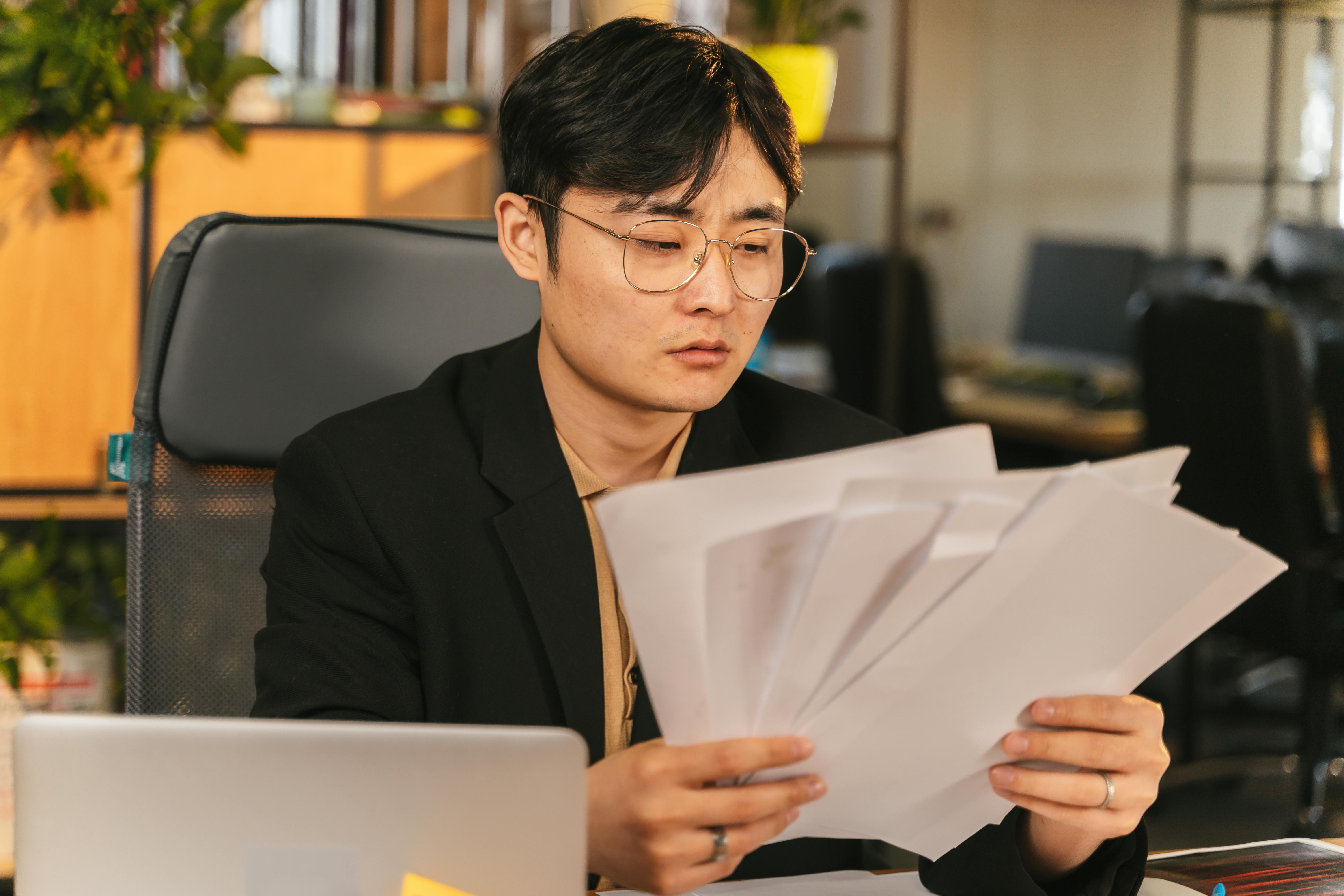 A man reviewing documents at his desk, analysing gross vs net salary and how to plan his monthly budget effectively.