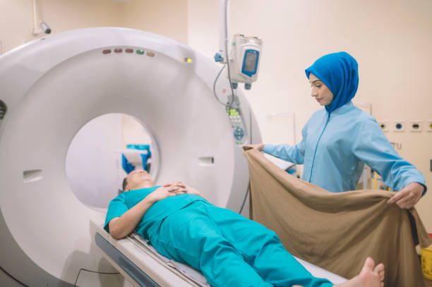 Seorang jururawat sedang membantu pesakit untuk menjalani pemeriksaan CT scan di hospital. 