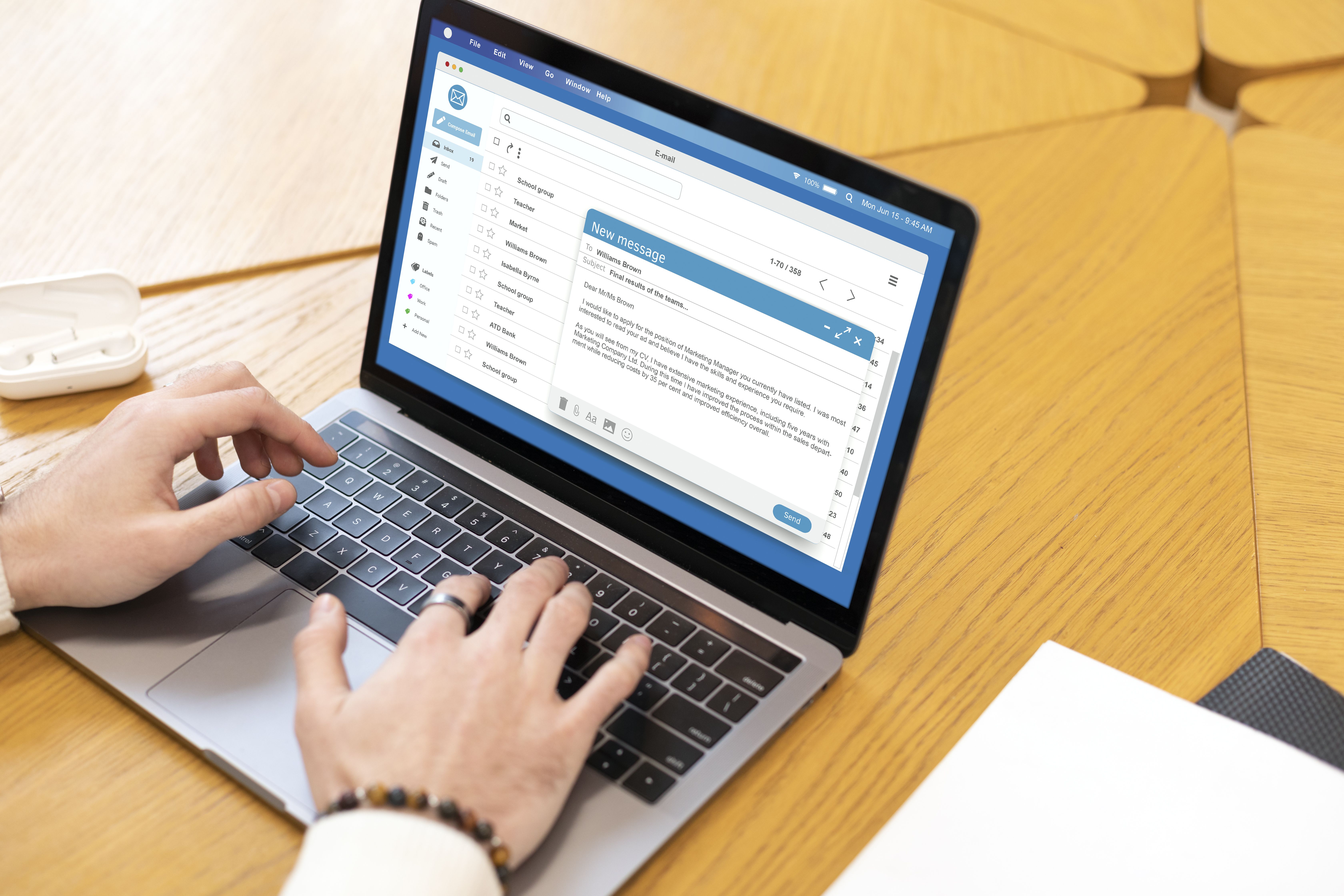 Close up of hands typing an email on an open laptop
